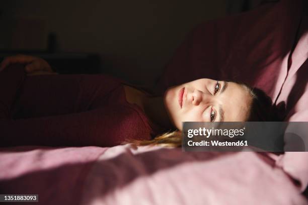 emotionally stressed woman lying on bed at home - sadness stock-fotos und bilder