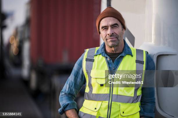 mature male driver leaning on truck - trucker stockfoto's en -beelden