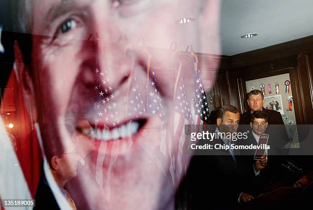 Speaker of the House John Boehner is reflected in a framed photograph of former President George W. Bush during a news conference at the Republican...