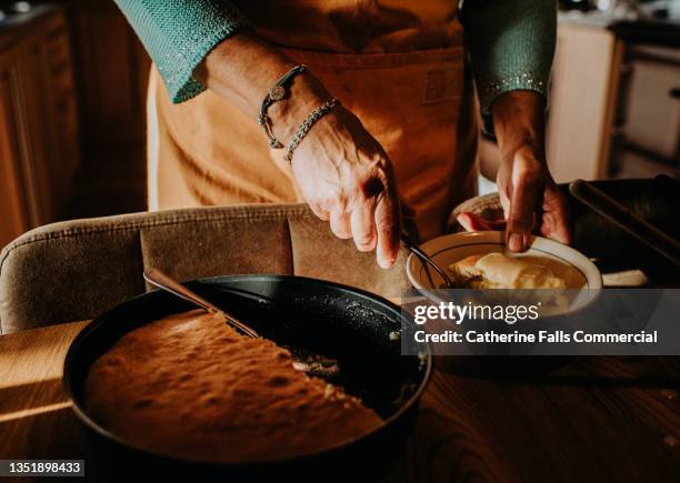 a woman serves a slice of homemade sponge pudding topped with custard - カスタード ストックフォトと画像