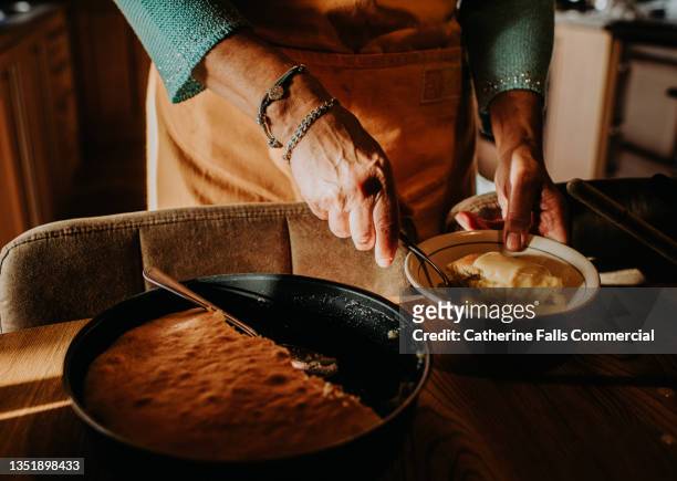 a woman serves a slice of homemade sponge pudding topped with custard - meals ready to eat stock pictures, royalty-free photos & images