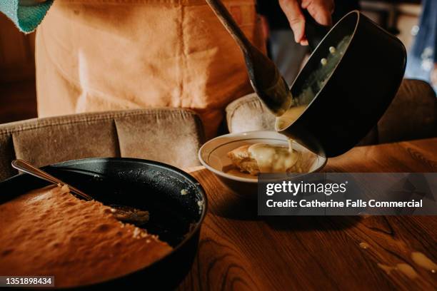 a woman pours custard from a saucepan onto fresh sponge pudding - cherimoya stock pictures, royalty-free photos & images