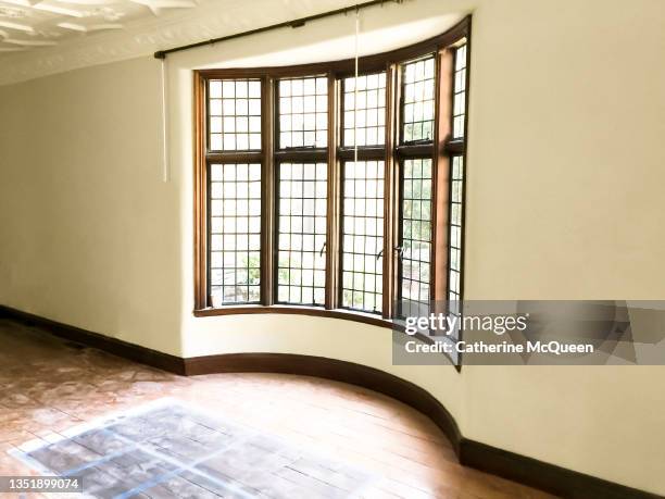 tudor home renovation: selecting color of new floor stain in front of leaded glass bay window - bay window interior stock pictures, royalty-free photos & images