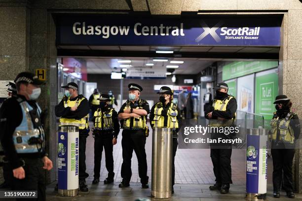 Police officers stand at the entrance to a train station during a demonstration by climate activists in central Glasgow on November 07, 2021 in...