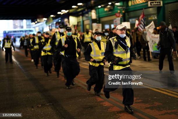 Police officers run to take up positions to safely block traffic along the route of a protest as demonstrators march through central Glasgow...