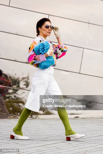 Influencer Salome Chaboki, wearing a multicolor mohair-blend knit sweater by Essential Antwerp, white bermuda shorts by Acne Studios, a blue faux fur...