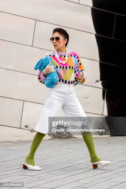 Influencer Salome Chaboki, wearing a multicolor mohair-blend knit sweater by Essential Antwerp, white bermuda shorts by Acne Studios, a blue faux fur...