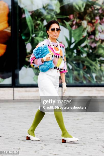 Influencer Salome Chaboki, wearing a multicolor mohair-blend knit sweater by Essential Antwerp, white bermuda shorts by Acne Studios, a blue faux fur...