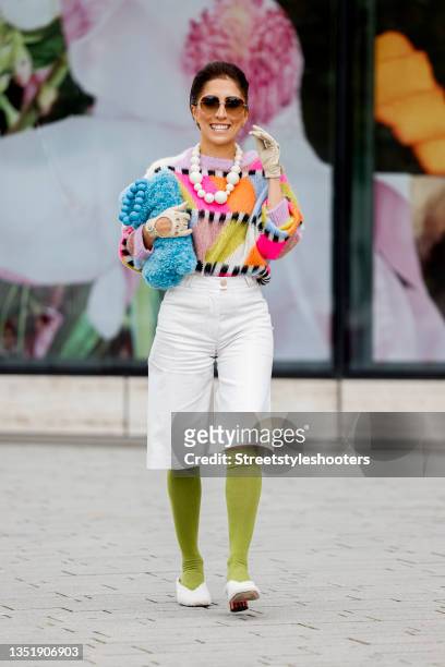 Influencer Salome Chaboki, wearing a multicolor mohair-blend knit sweater by Essential Antwerp, white bermuda shorts by Acne Studios, a blue faux fur...