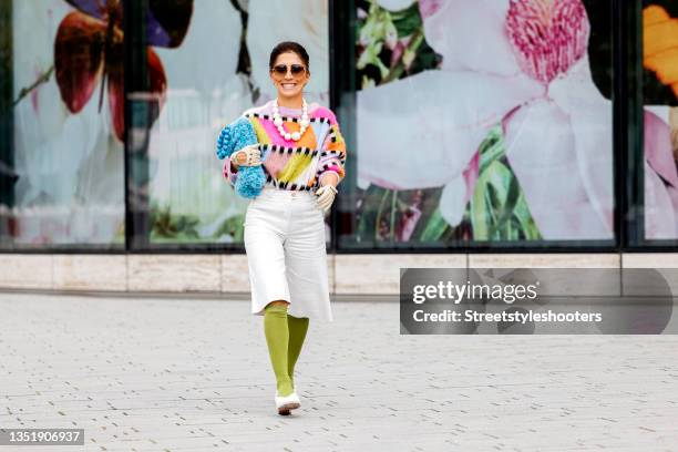 Influencer Salome Chaboki, wearing a multicolor mohair-blend knit sweater by Essential Antwerp, white bermuda shorts by Acne Studios, a blue faux fur...