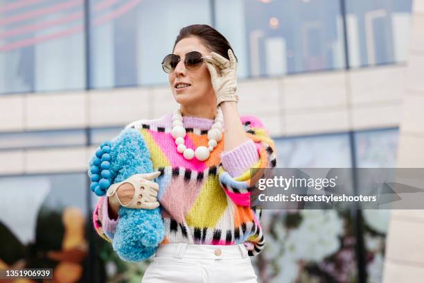 Influencer Salome Chaboki, wearing a multicolor mohair-blend knit sweater by Essential Antwerp, white bermuda shorts by Acne Studios, a blue faux fur...