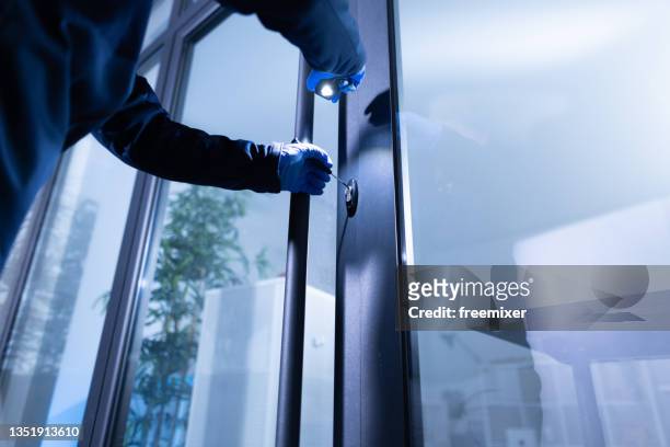 thief holding flashlight and trying to open glass door and break into office - penetrating stock pictures, royalty-free photos & images