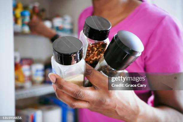 woman grabs spices from pantry - mature woman herbs stock pictures, royalty-free photos & images