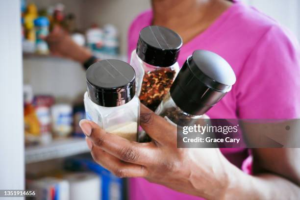 woman grabs spices from pantry - kryddning bildbanksfoton och bilder