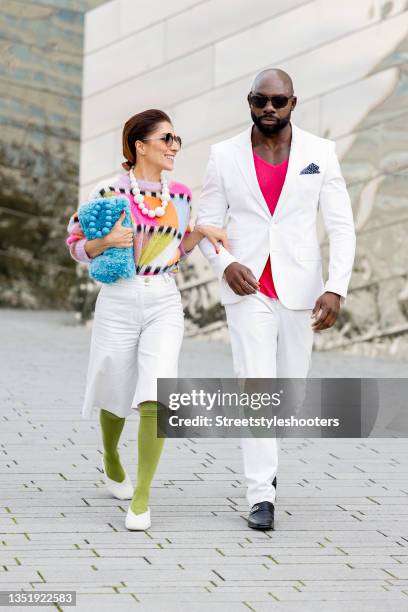 Influencer Salome Chaboki, wearing a multicolor mohair-blend knit sweater by Essential Antwerp, white bermuda shorts by Acne Studios, a blue faux fur...