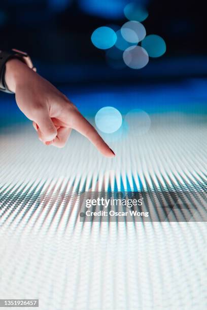 close-up of female hand touching illuminated digital display in the dark. - points of light gala stockfoto's en -beelden