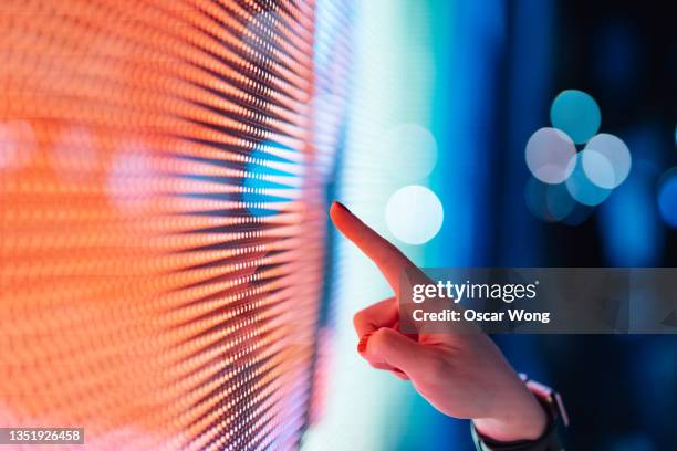 close-up of female hand touching illuminated digital display in the dark. - technology 個照片及圖片檔