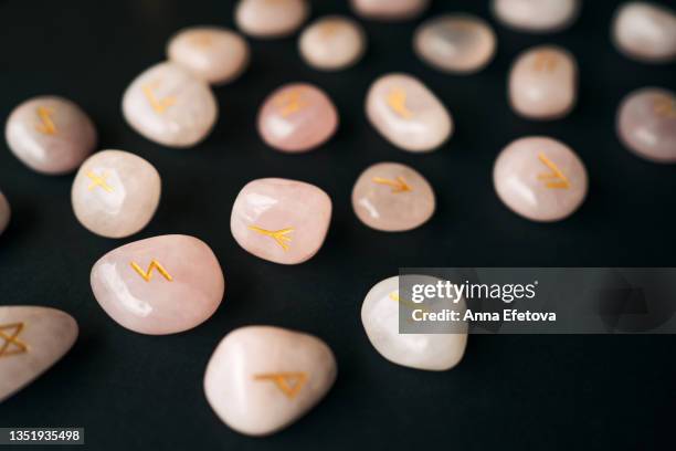 many runes made of rose quartz with gold text arranged on black background. concept of magic esoteric rituals. macro photography in flat lay style - rune symbols stock pictures, royalty-free photos & images
