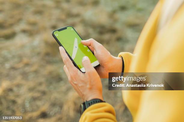 man explorer using a travel app or map on smartphone during his hike. - geocaching stock pictures, royalty-free photos & images