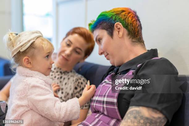 same sex couple relaxing at home with their daughter - lesbian stock pictures, royalty-free photos & images
