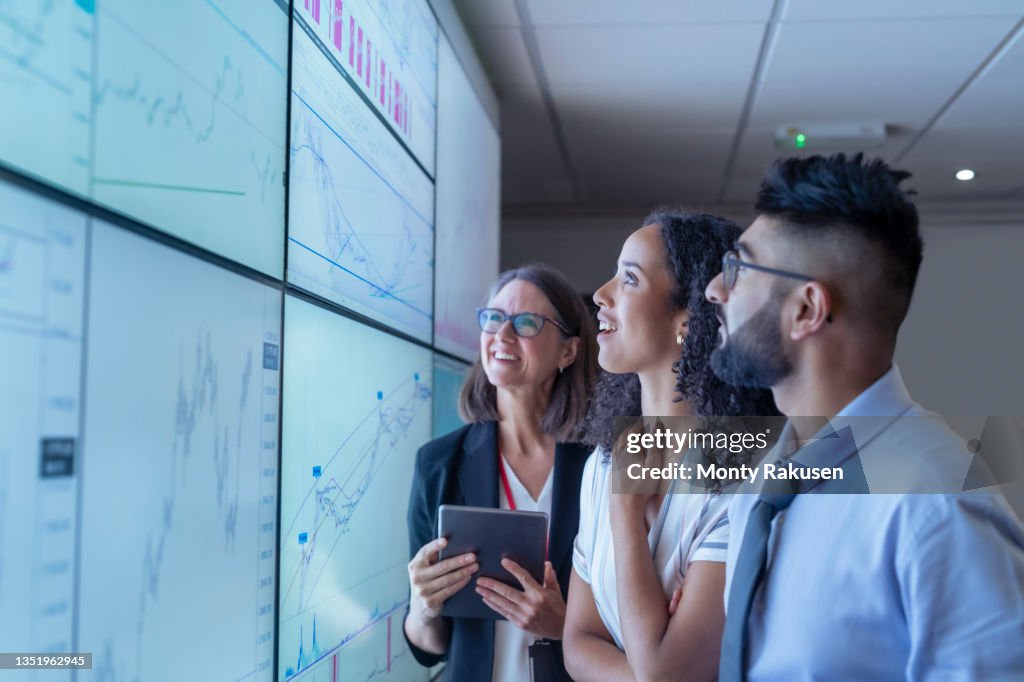 UK, York, Business people discussing charts on interactive screens