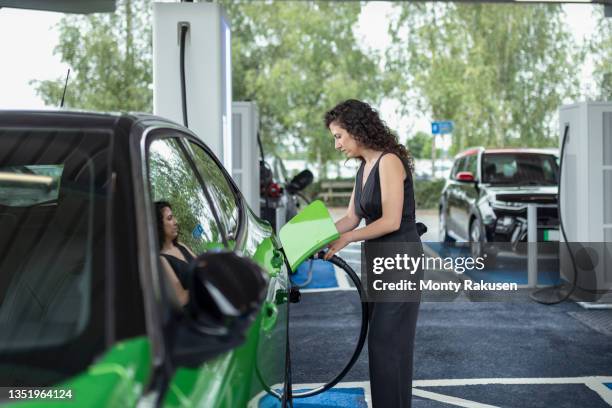 uk, york, woman charging electric car at charging station - coche eléctrico coche de combustible alternativo fotografías e imágenes de stock