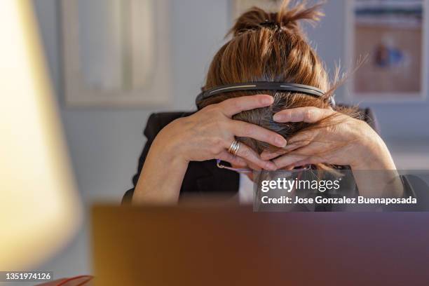 dejected middle-aged woman - working at home using laptop and headphones with microphone - screaming of hopelessness by emotional stress caused by oppressive job. madrid, spain - frustrated stock pictures, royalty-free photos & images