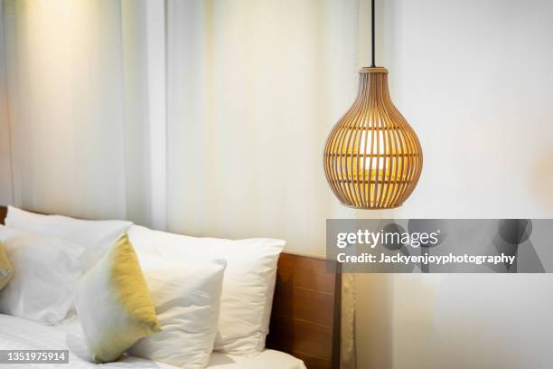 lightbulbs protected by wire hang in front of a white wall inside bedroom - lámpara eléctrica fotografías e imágenes de stock