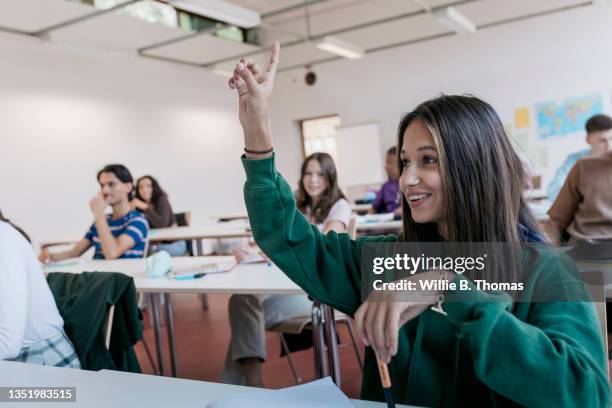 high school student raising her hand in class - school classroom stock-fotos und bilder