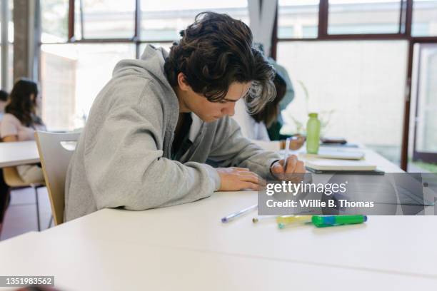 high school student concentrating on written assignment in class - boy writing stock pictures, royalty-free photos & images