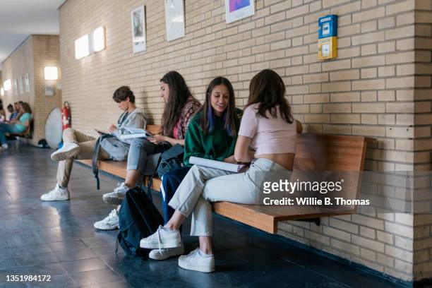 high school students sitting in hallway between lessons - bauchfreies oberteil stock-fotos und bilder