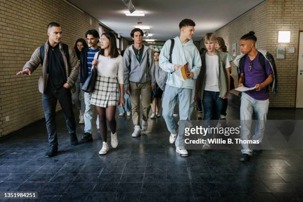 high school students walking down corridor - sekundarstufe stock-fotos und bilder