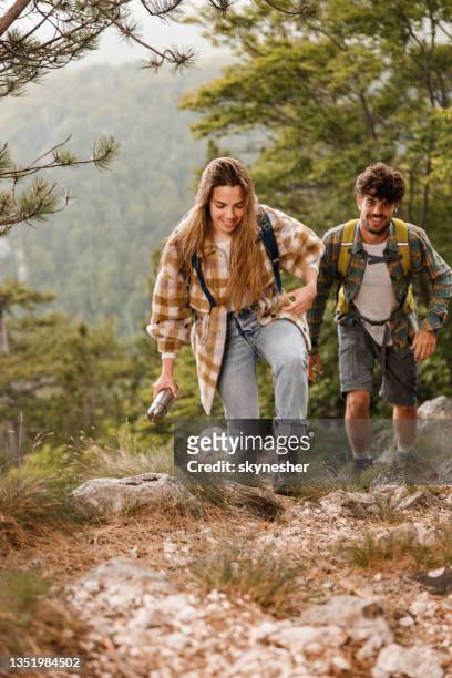 happy couple of backpackers climbing the mountain on rainy day. - terra em estado natural imagens e fotografias de stock