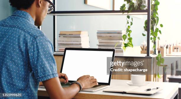 cropped shot of an unrecognizable man sitting alone in a cafe and using his laptop for remote work - space man stockfoto's en -beelden