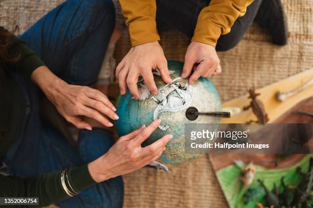 top view of unrecognizable young man with down syndrome with his tutor learning about dinosaurs, homeschooling. - desktop globe stock-fotos und bilder