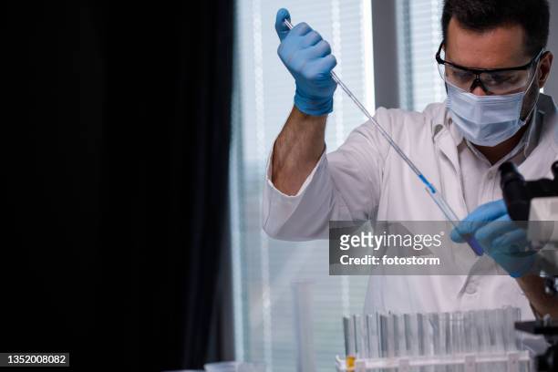 male scientist preparing a test tube with blue liquid for analysis - blue glove stock pictures, royalty-free photos & images
