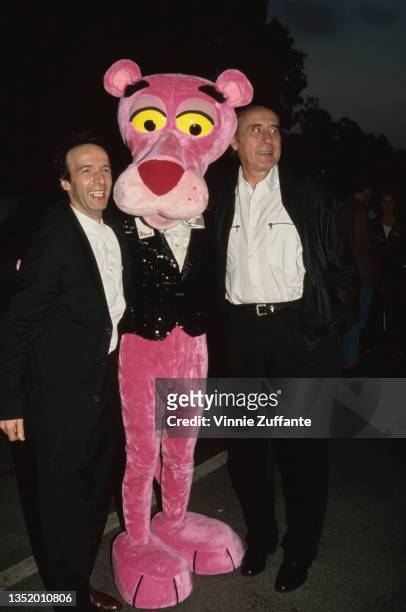 Italian actor and comedian Roberto Benigni and American composer Henry Mancini stand either side of an person wearing a Pink Panther costume at the...