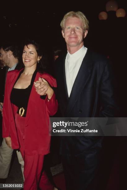 American writer and actress Mara Purl, wearing a red trouser suit, with American actor Ed Begley Jr attending the Los Angeles premiere of 'Hero' held...