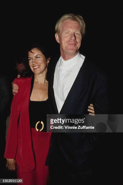 American writer and actress Mara Purl, wearing a red trouser suit, with American actor Ed Begley Jr attending the Los Angeles premiere of 'Hero' held...