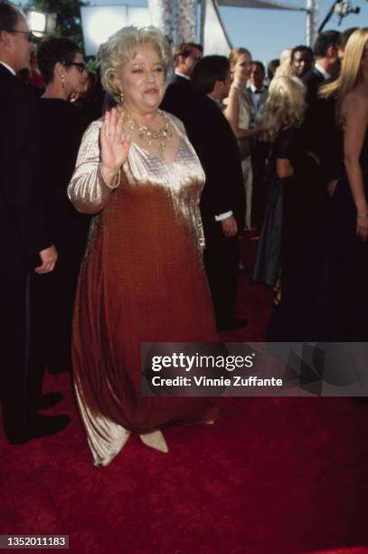 American actress Kathy Bates, the red carpet reflected in her gold evening gown, waving as she attends the 51st Primetime Emmy Awards, held at the...