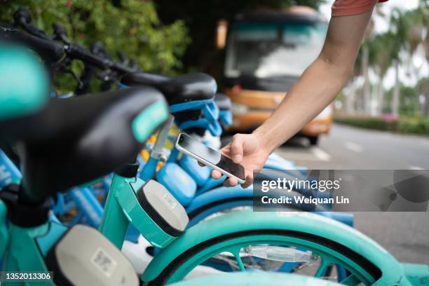 asians use their smartphones to scan the qr code on the bicycle to unlock the bicycle - public transportation fotografías e imágenes de stock