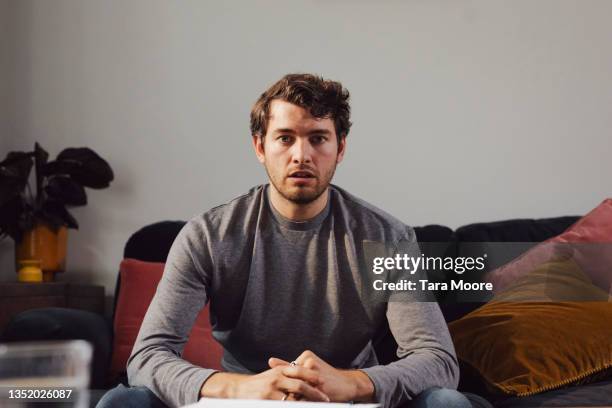 young man facing the camera looking worried. - man brown hair stock pictures, royalty-free photos & images