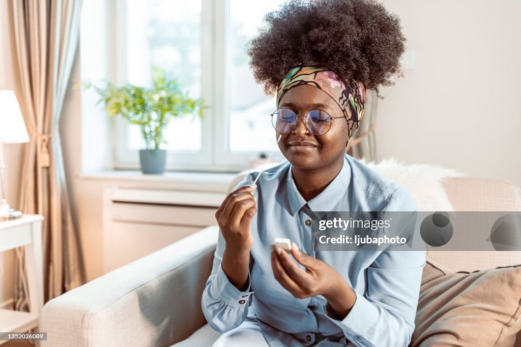 Woman at home using a nasal swab for covid 19 detection