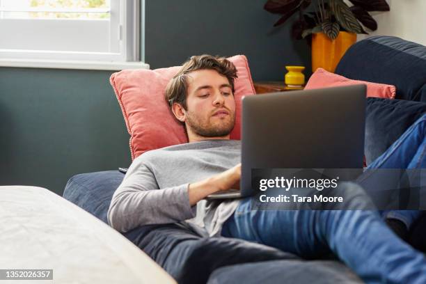 young man using laptop. - young man laptop couch photos et images de collection