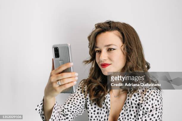 portrait of young woman using smart phone against white background - beautiful romanian women stock pictures, royalty-free photos & images
