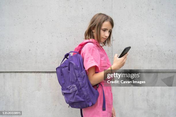 teenage girl using cell phone outside - school bag stockfoto's en -beelden