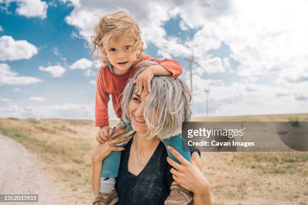 mothe with toddler on her shoulders in field - fuel and power generation stock-fotos und bilder