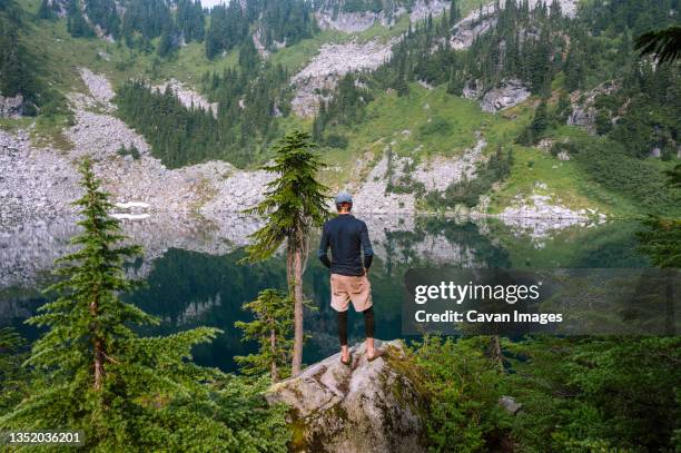 hiker taking in the serene views of an alpine lake in washington - wanderweg-pacific-crest-trail stock-fotos und bilder