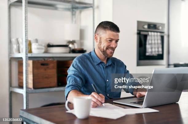 shot of a businessman working from home making notes while using his laptop - 40 2018 stock pictures, royalty-free photos & images