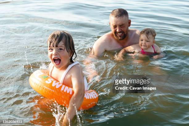 the boy swims with swimming circle and girl swims with daddy - cavan images stock-fotos und bilder